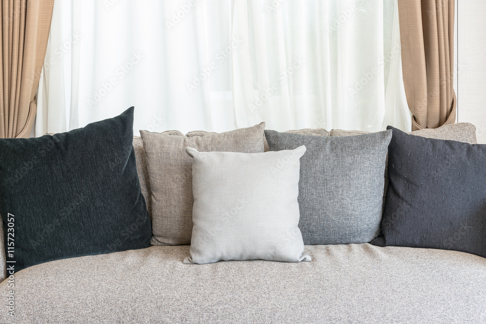 set of pillows on modern sofa with white curtain