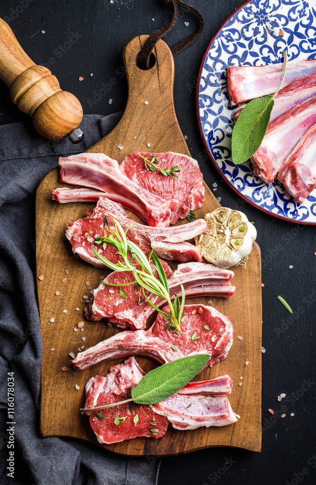 深色背景下的乡村木板上的生生生羊肉排，配香草和香料