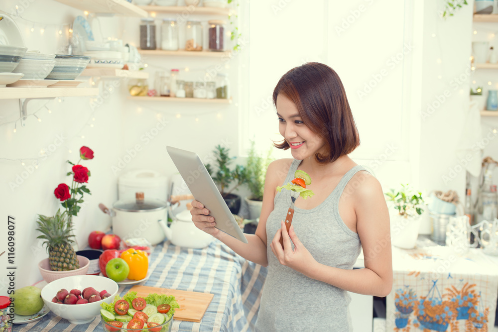 亚洲年轻女性吃健康食品并使用平板电脑