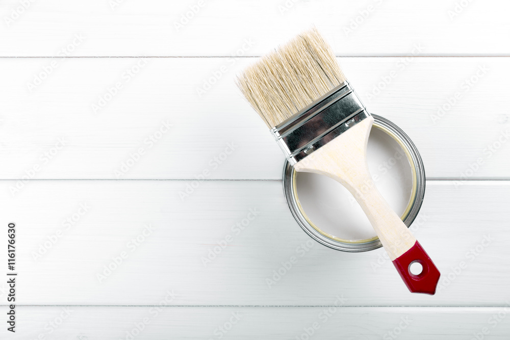 paint can with paintbrush on white wooden background with copysp