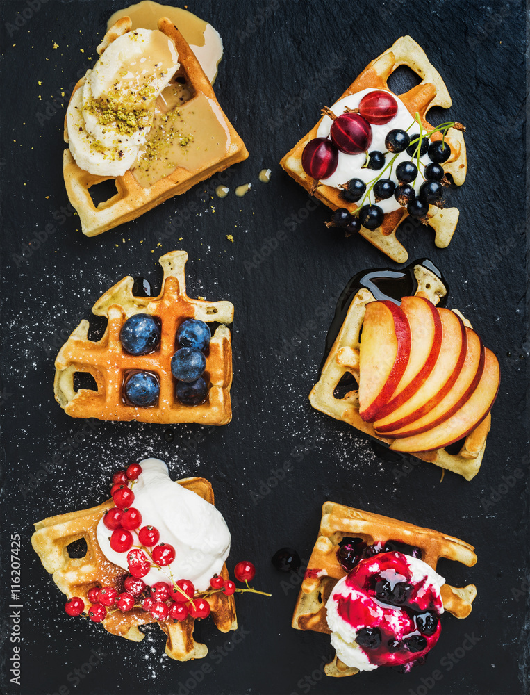 Warm belgian homemade waffles with fresh garden berries, fruit and ice cream on dark slate stone bac