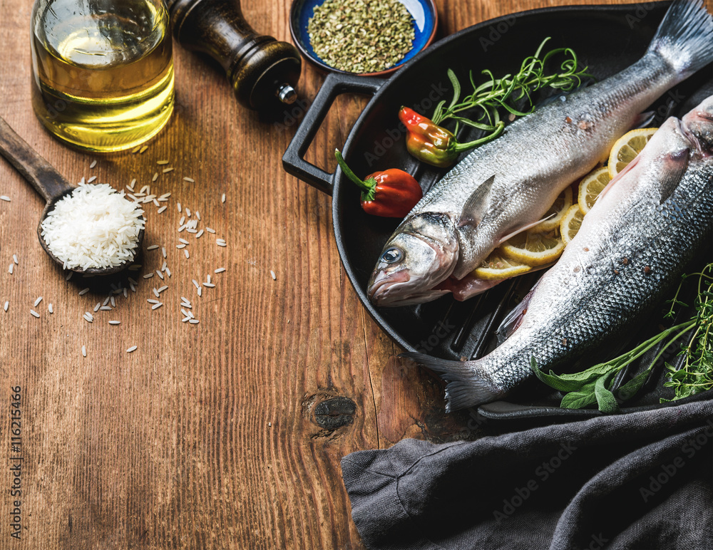 Ingredients for cookig healthy fish dinner. Raw uncooked seabass  with rice, olive oil, lemon slices