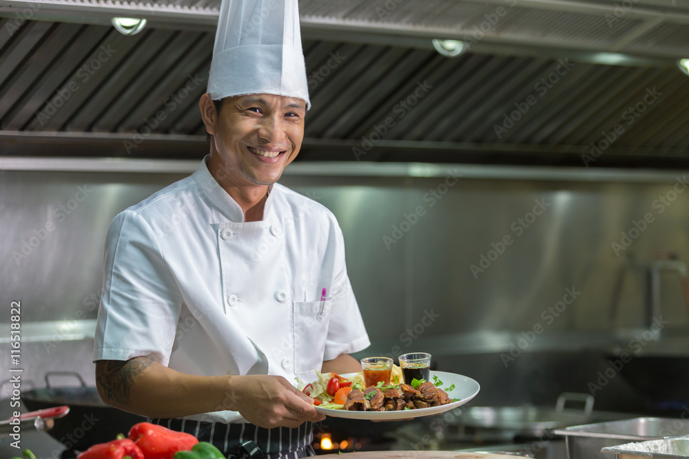 Portrait of a smiling male chef with cooked food standing in the kitchen, Chef Thailand