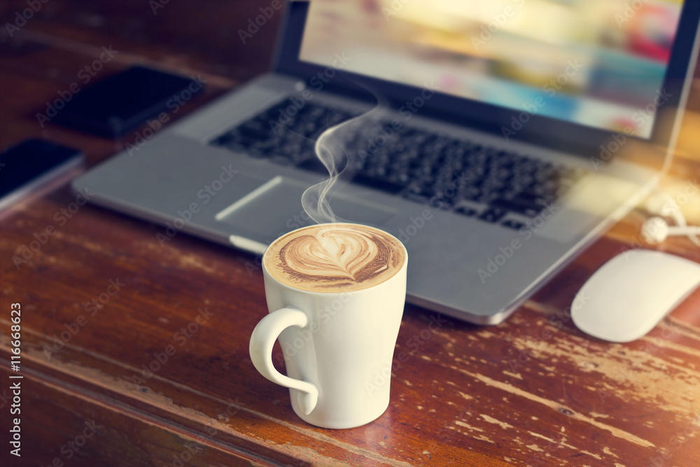 coffee cup with laptop, mouse and earphone on old wooden table 