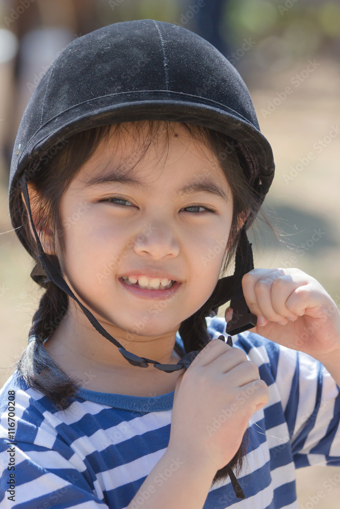 Closeup portrait of a pretty Asian elementary horse rider in her helmet