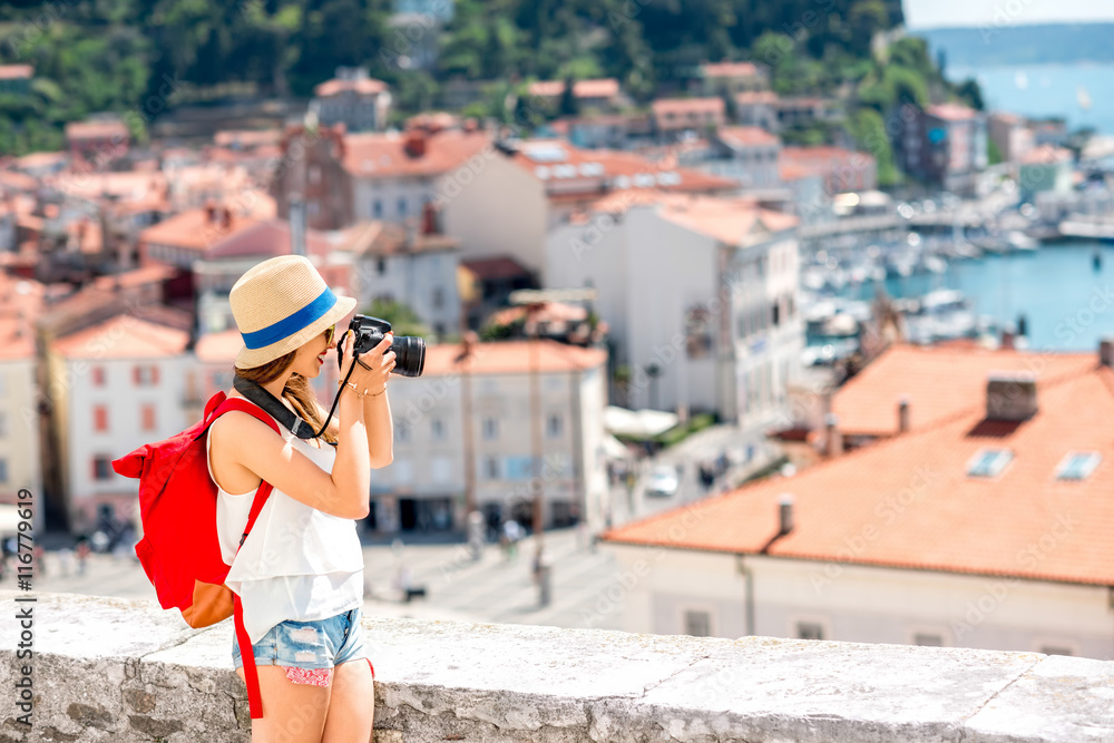 背着红色背包的年轻女性旅行者用相机拍摄皮兰古镇。旅行