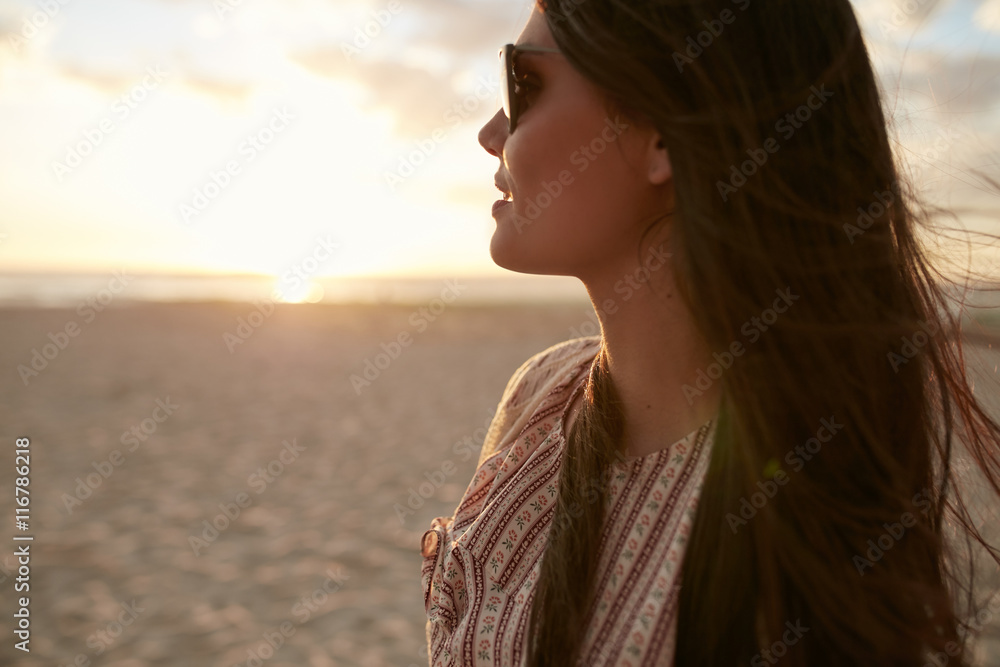 Beautiful young woman on the beach at sunset