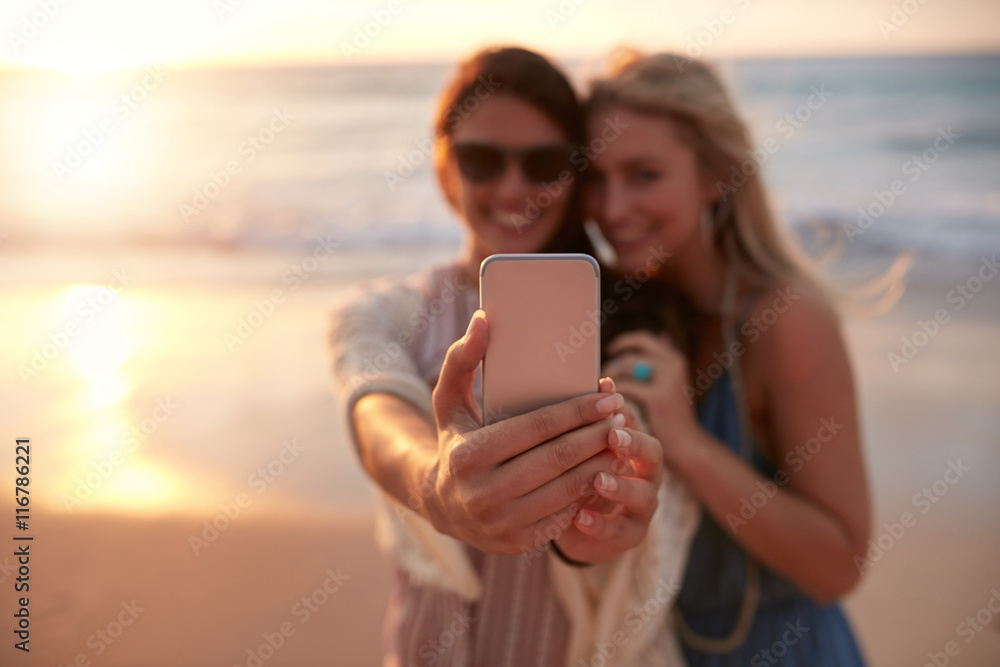 Female friends taking selfie with beach sunset