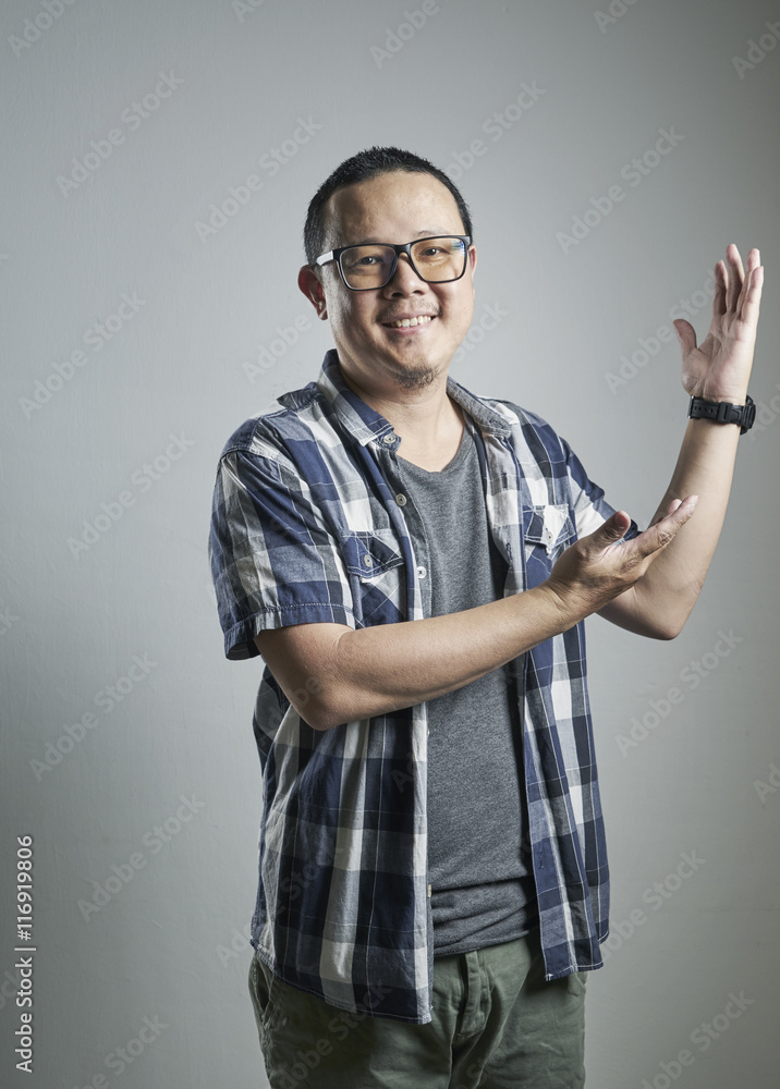 Young Asian man showing welcome sign isolated on grey background.