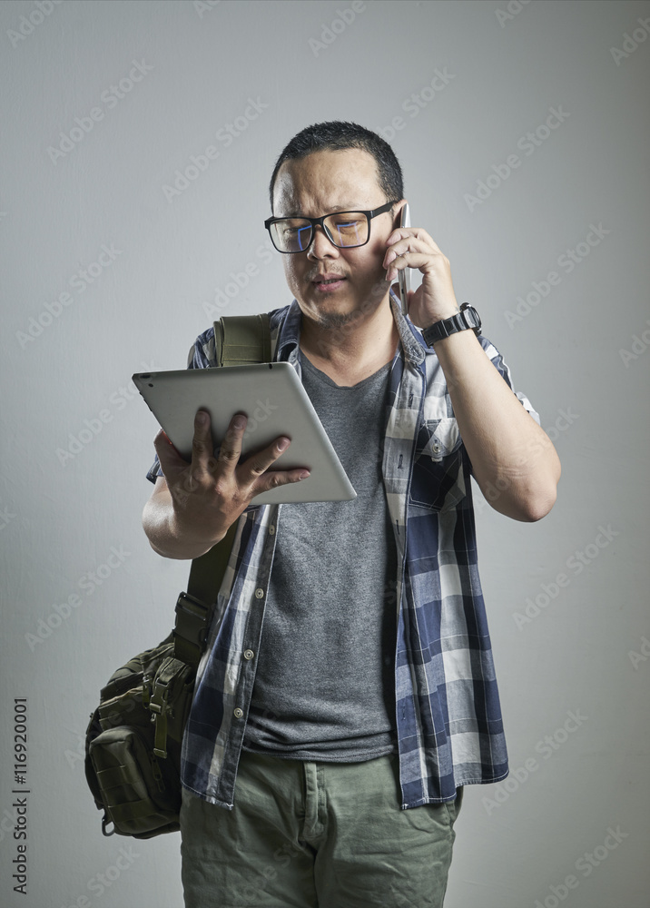 portrait of young asian man talking on the phone and looking on digital pad