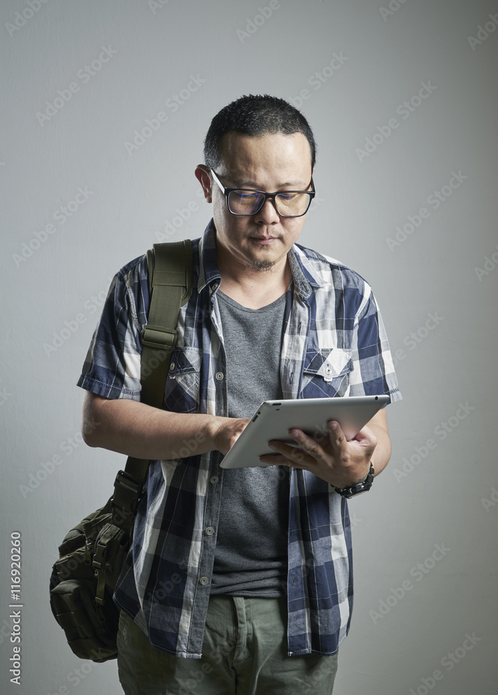 Portrait of a  stress asian guy holding a digital pad up on plain background