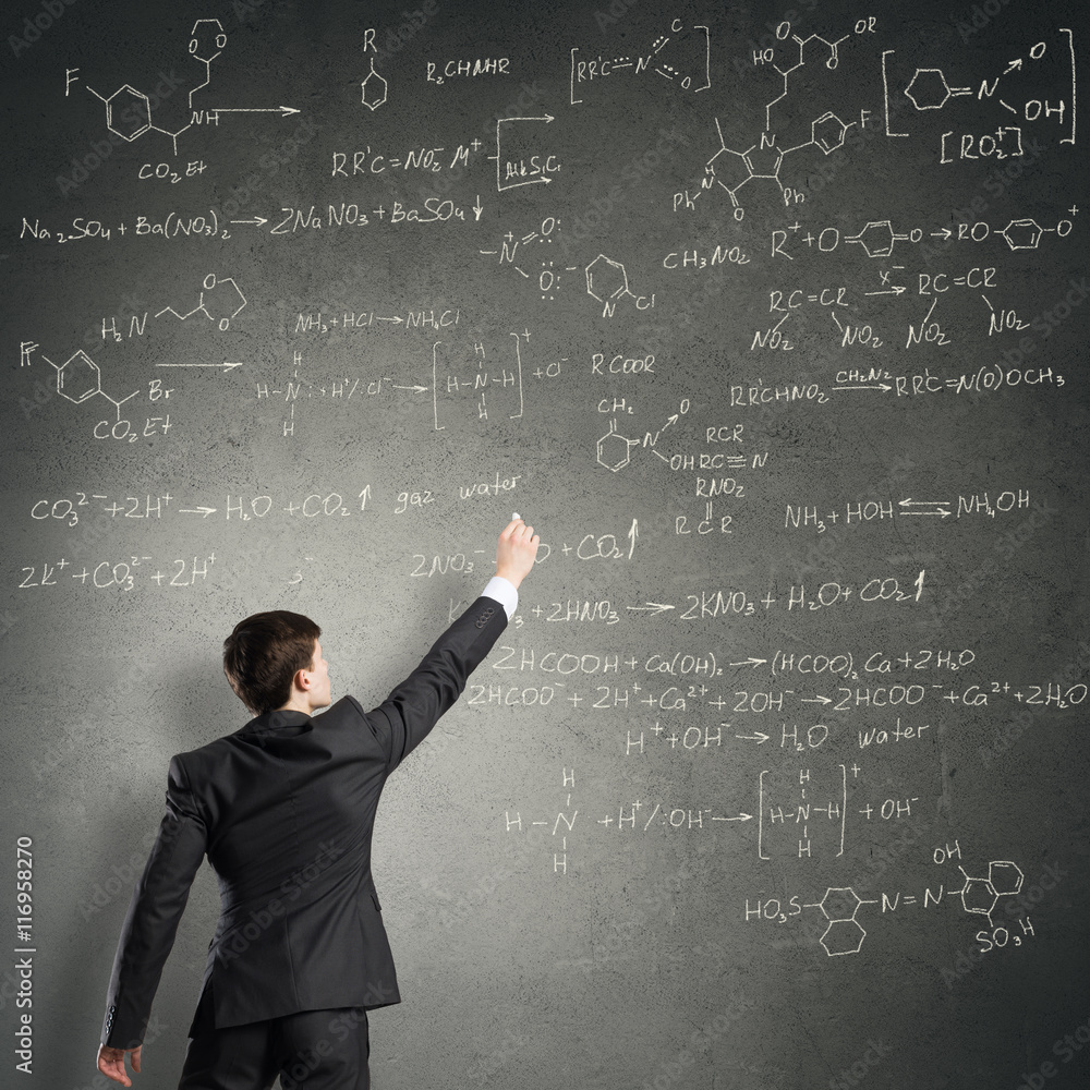 Scientist writing formulas on chalkboard