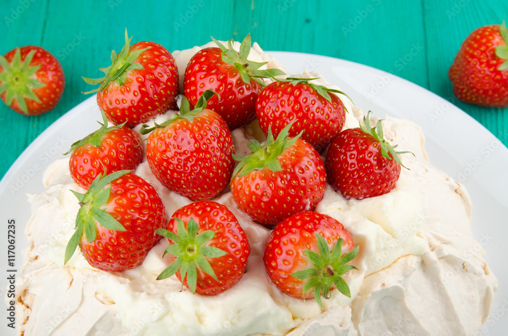 Pavlova cake with strawberry on rustic background.