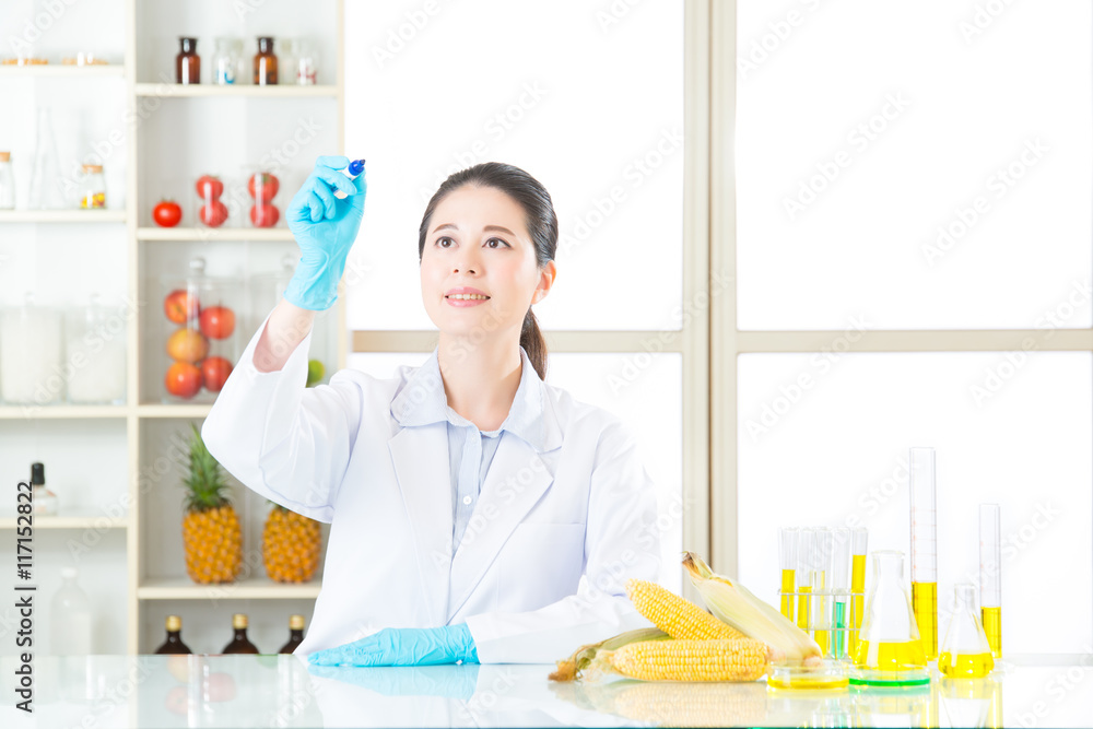 Asian female scientist recording the result on writing glass in