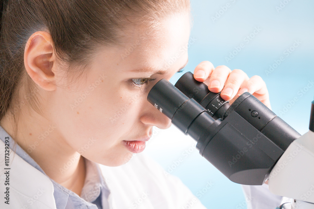 Young woman student work in microbiological laboratory with microscope