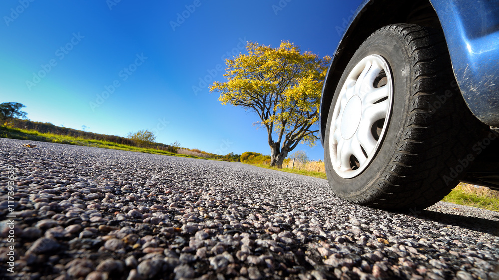 Car wheel on asphalt road in autumnal evening