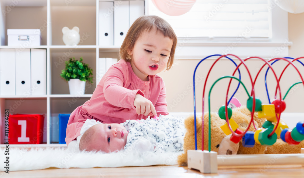 Happy toddler girl playing with her baby sibling