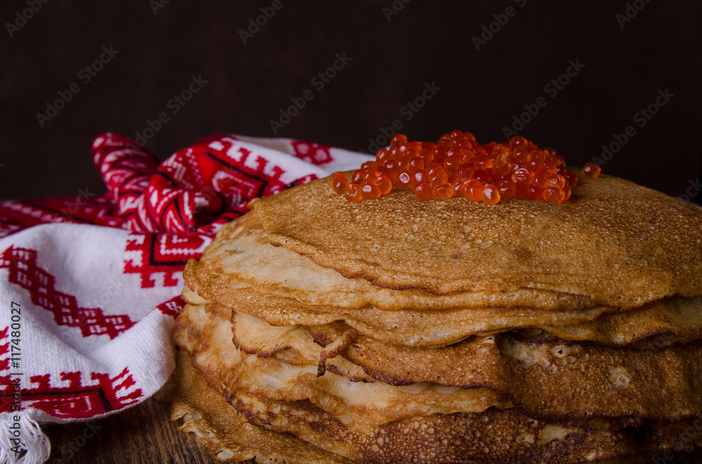 传统俄罗斯煎饼配红色鱼子酱，木质乡村背景。Maslenitsa。