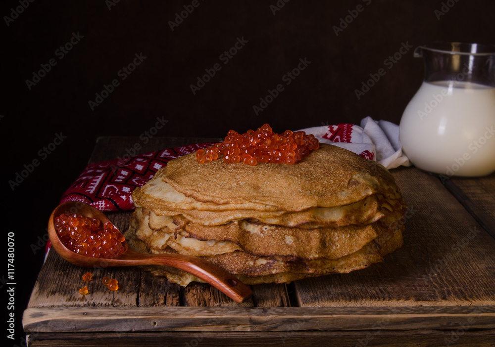 传统的俄罗斯煎饼配红色鱼子酱，木质乡村背景。Maslenitsa。