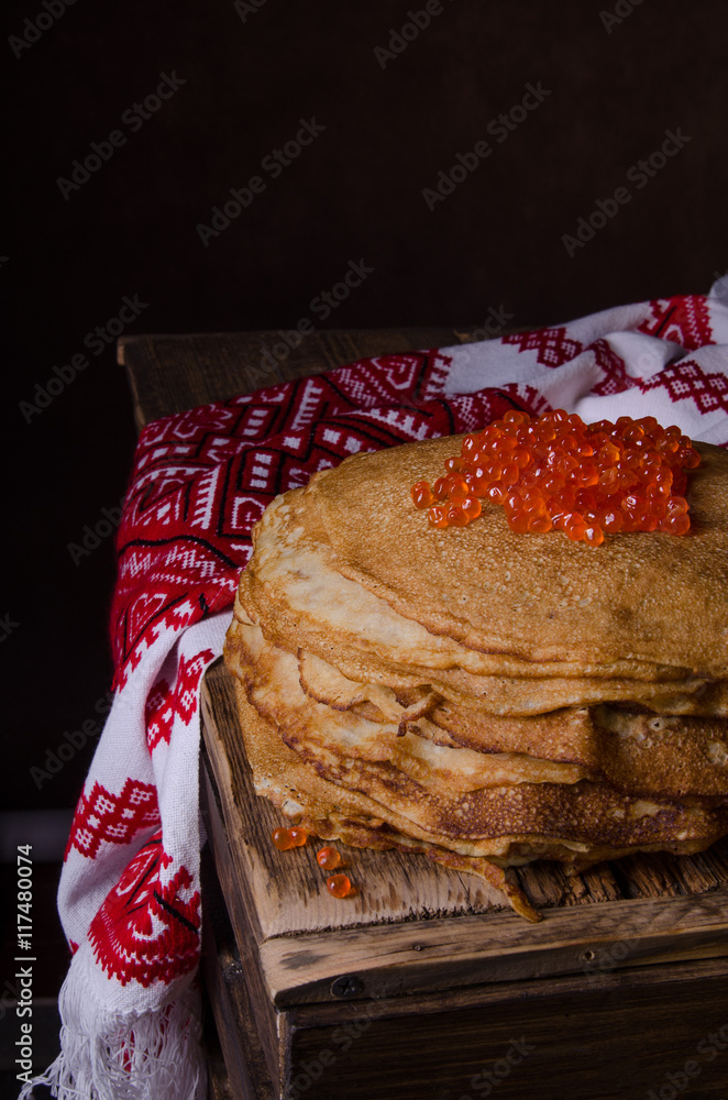 传统的俄罗斯煎饼配红色鱼子酱，木质乡村背景。Maslenitsa。