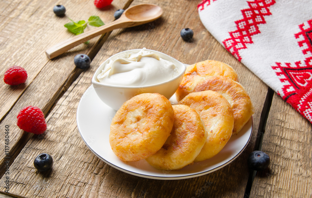 Russian cottage cheese pancakes with raspberries on wooden background. Selective focus.