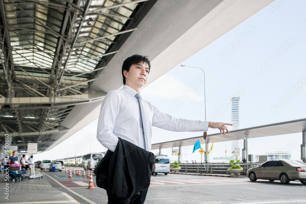 Young Asian businessman calling taxi in airport.