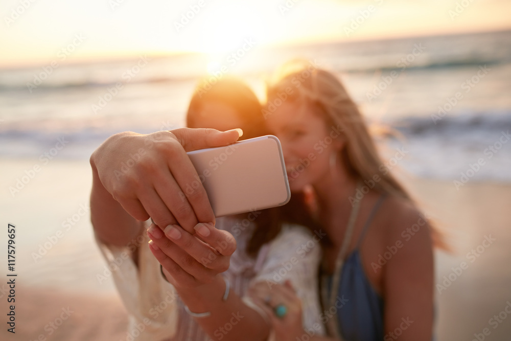 Female friends on taking selfie on the beach