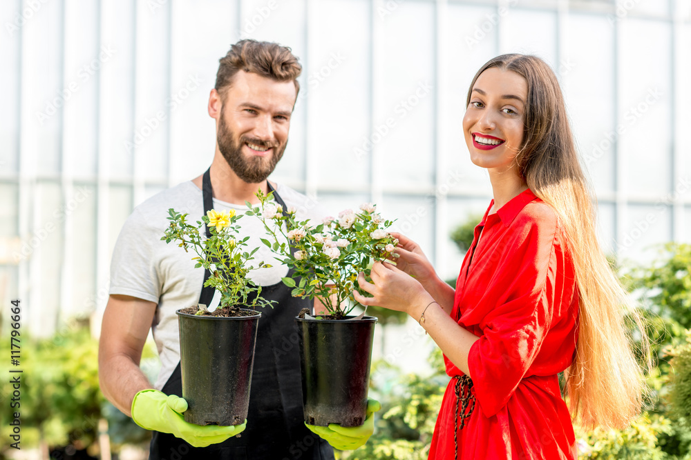 英俊的卖花人站在植物店里帮助女买家选花。顾客