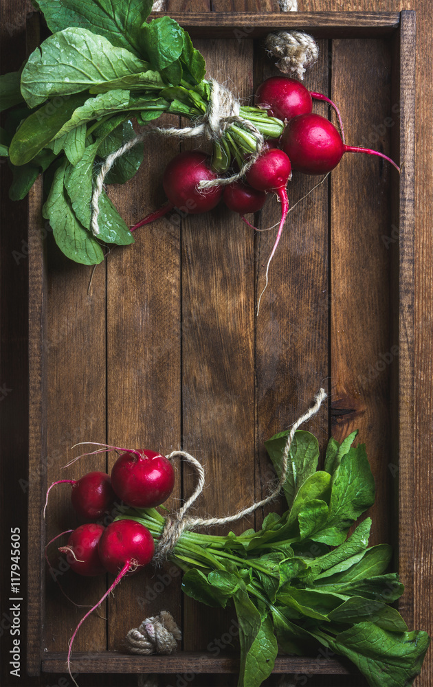 Fresh radish banches on wooden tray background. Top view, copy space, vertical