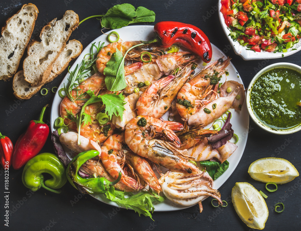 Plate of roasted tiger prawns and pieces of octopus with fresh leek, vegetable salad, peppers, lemon