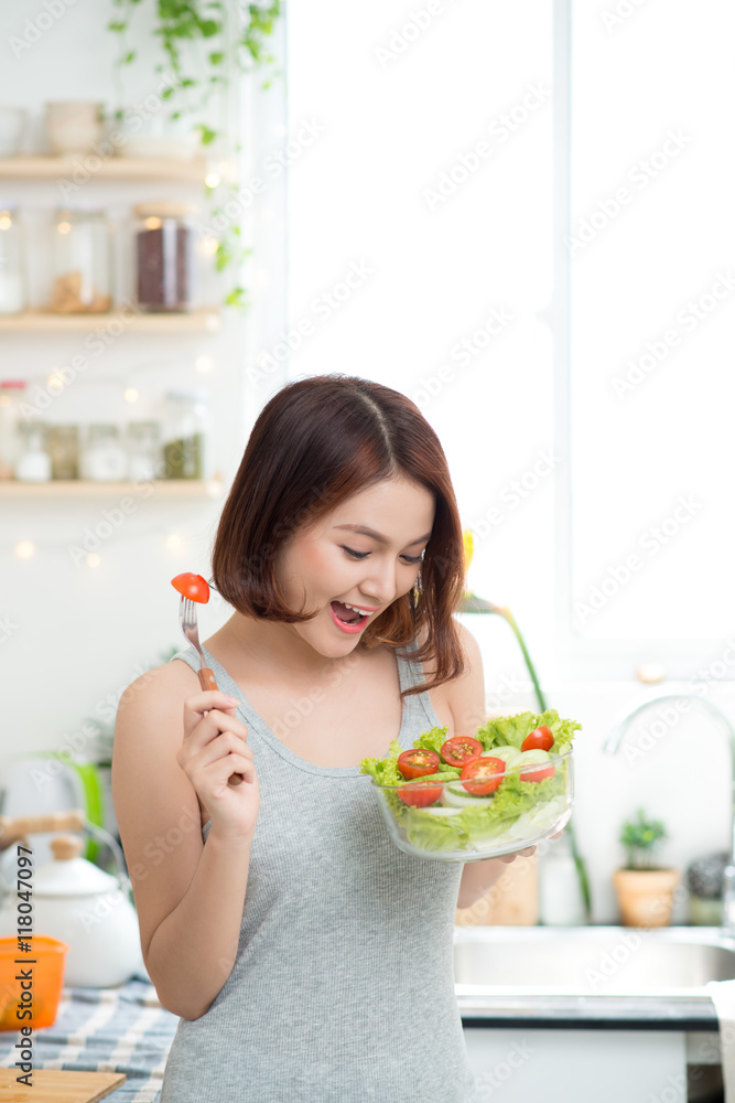 Beautiful young asian girl eating salad. smiling happy girl eati