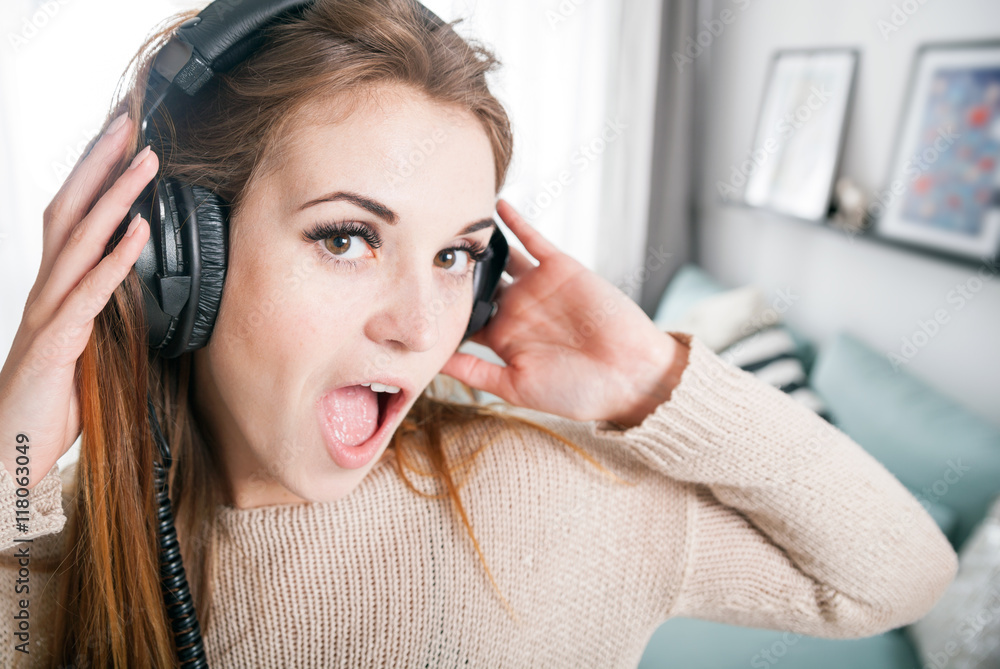 Portrait young woman with headphones listening to music at home