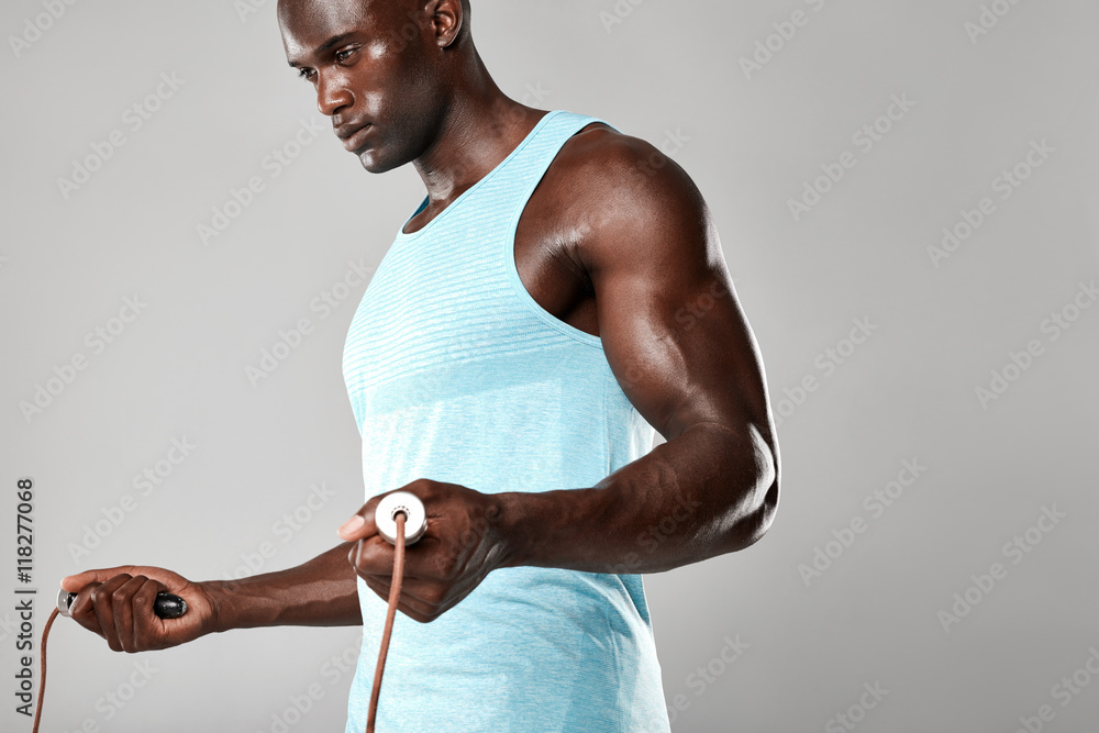 Muscular young man exercising with jumping rope