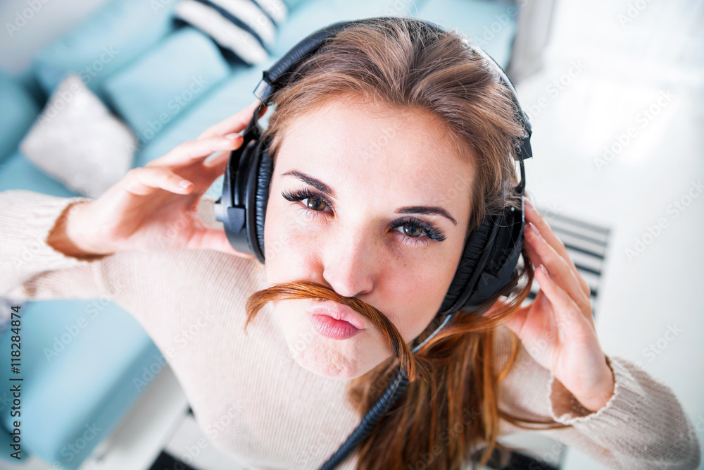 Portrait young woman with headphones listening to music at home