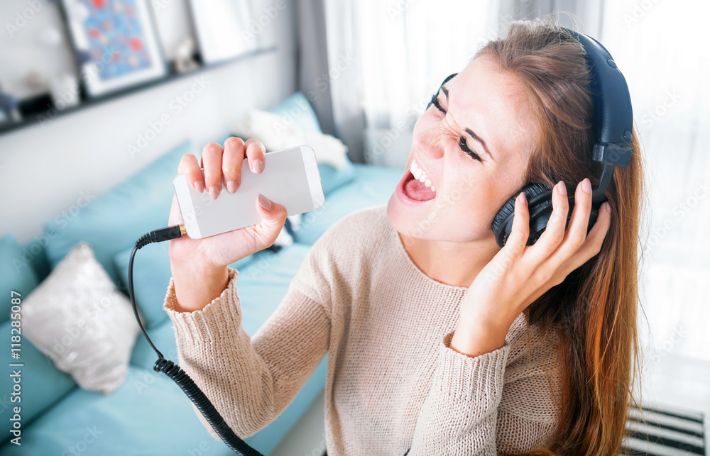 Woman with headphones singing and listening to music at home