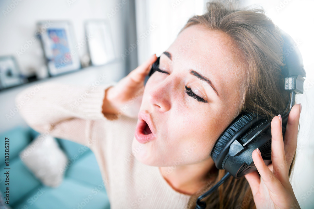 Woman with headphones singing and listening to music at home