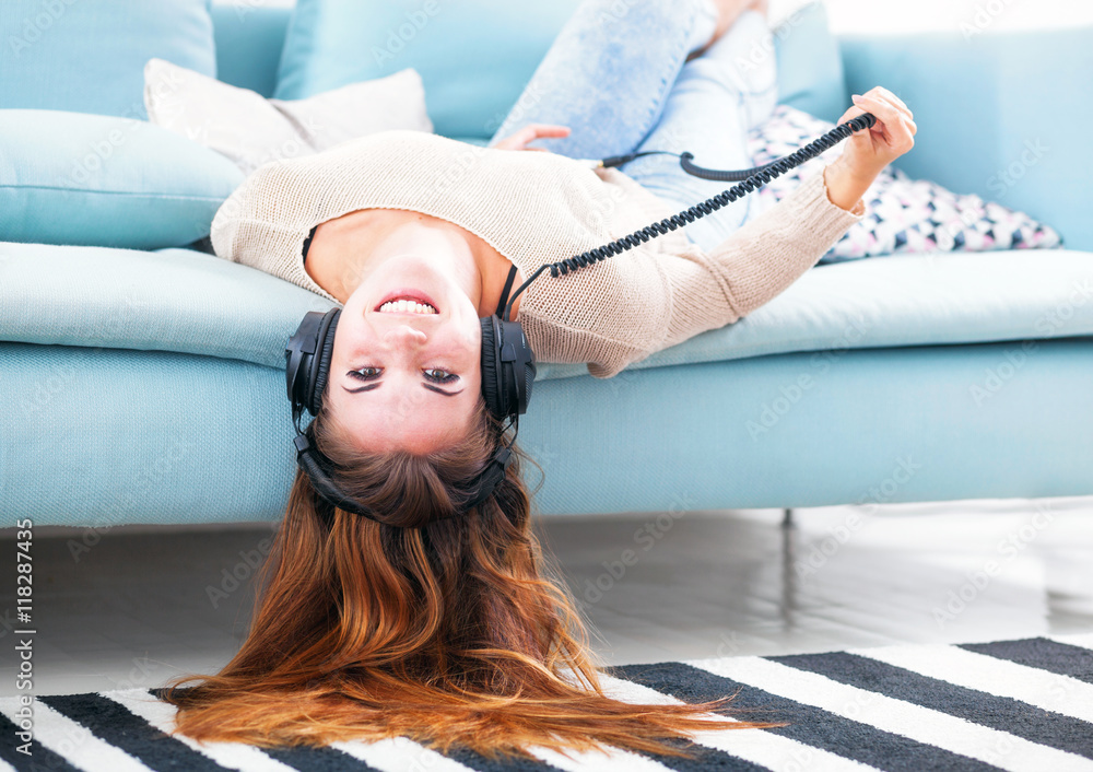 Woman with headphones lying and listening to music at home