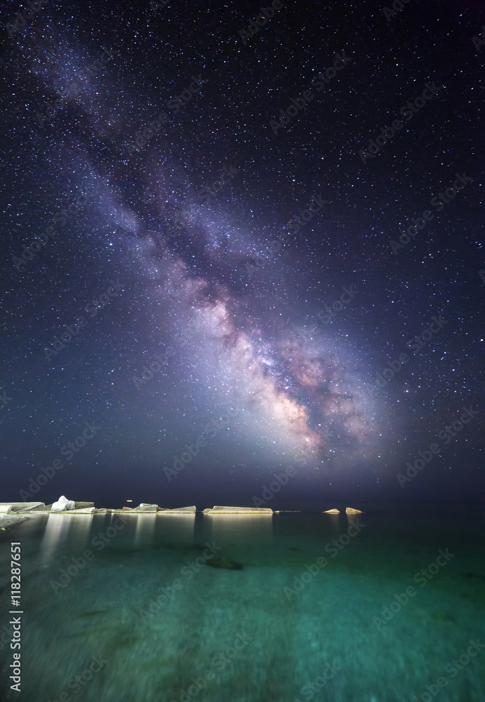 Night landscape with milky way at the sea coast with stones. Starry sky