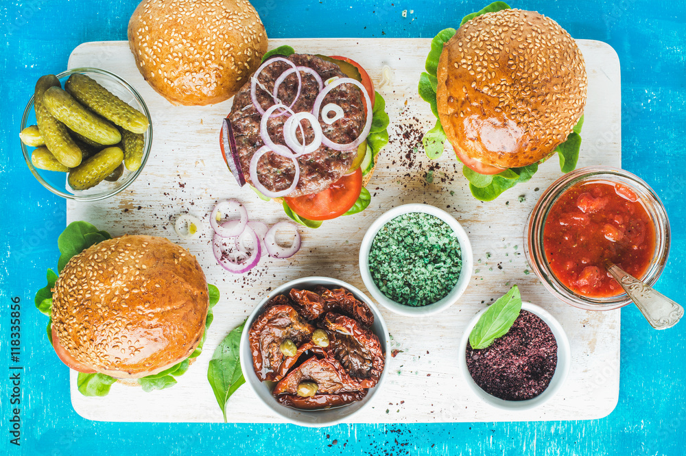 Homemade beef burgers with onion rings, pickles, fresh vegetables, spices, sun-dried tomatoes and to