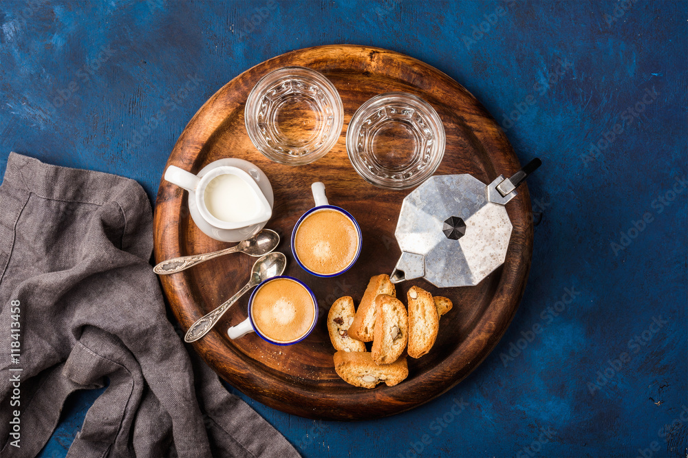 Coffee espresso in cups with italian cantucci, cookies and milk in jug on wooden serving round board