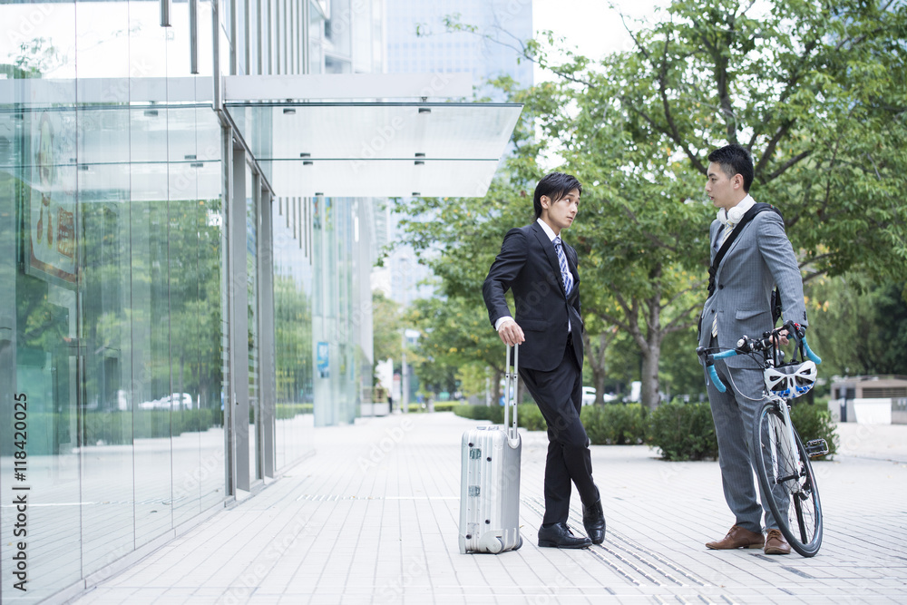 Two businessmen are talking while holding a bicycle