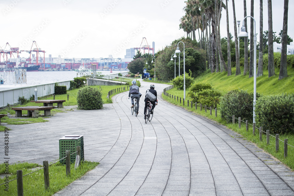 两名商人戴着头盔在公园里骑公路自行车