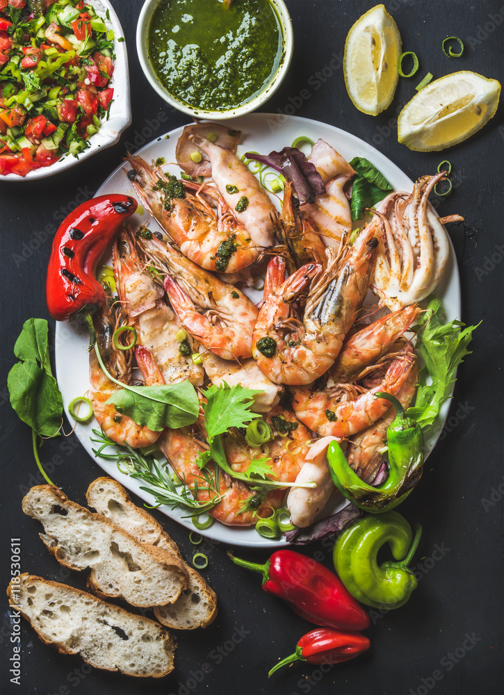 Plate of roasted tiger prawns and pieces of octopus with fresh leek, vegetable salad, peppers, lemon