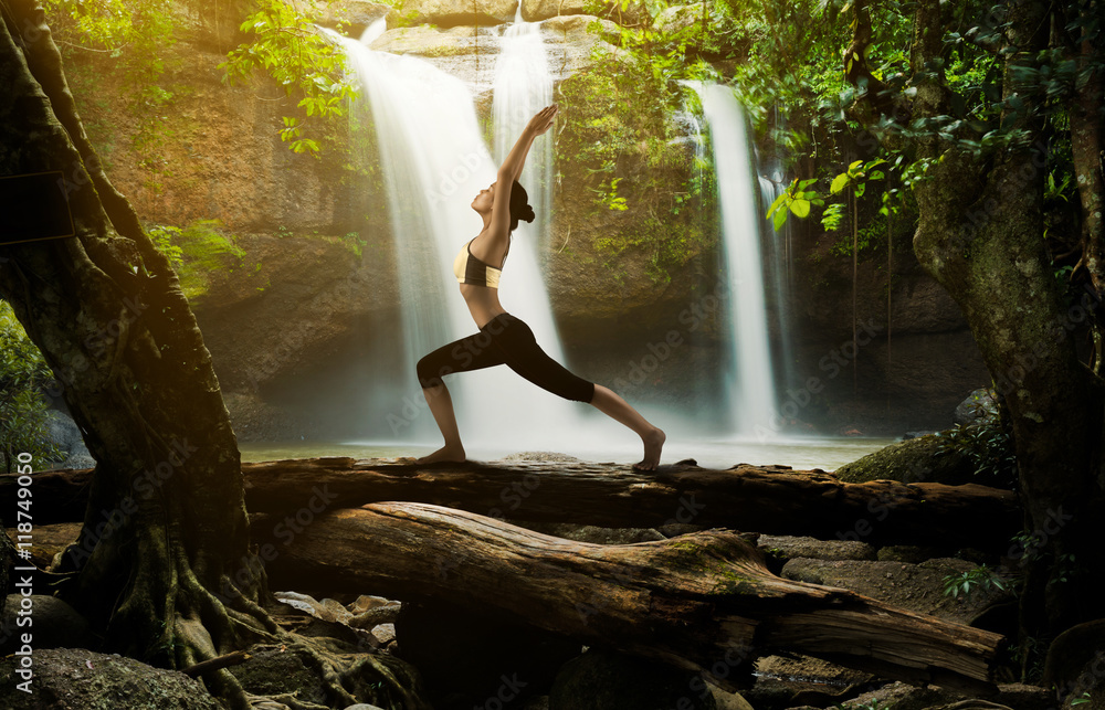 Young woman in a yoga pose at the waterfall, she felt relaxed. T