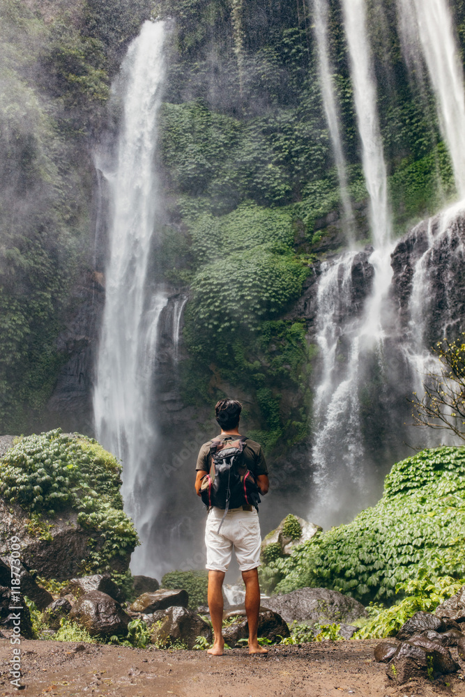 Young male hiker looking at waterfall