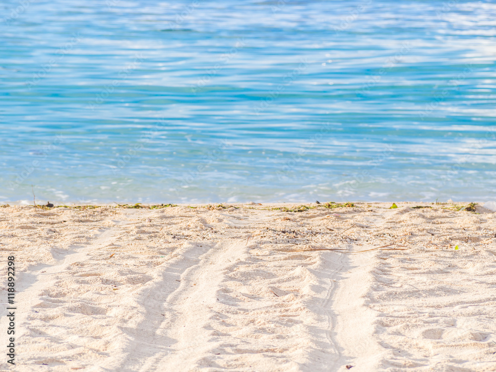 Wheel tracks on the beach and blurry blue sea background