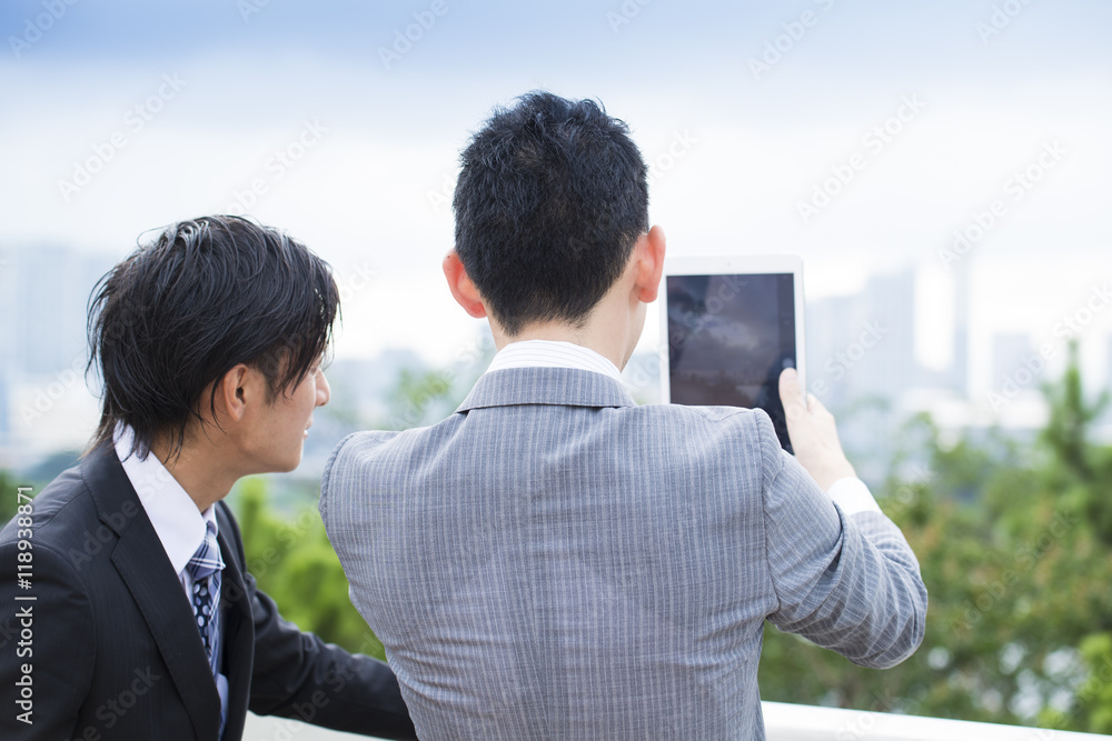 Two businessmen are looking at electronic tablet together