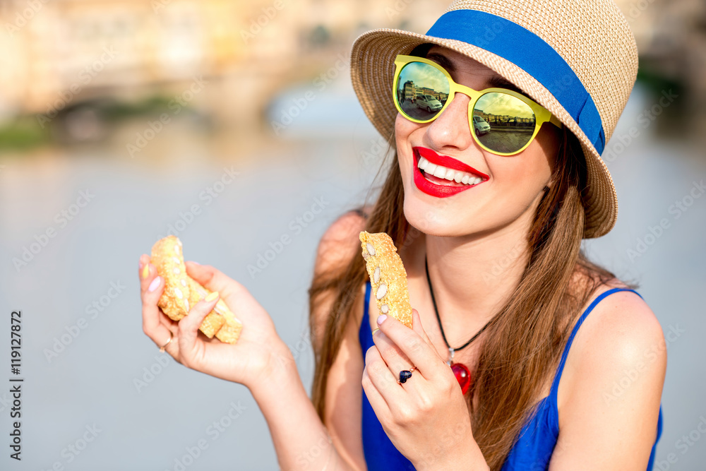 Young female tourist in the blue dress and hat eating cantuccini in Florence city. Cantuccini is tra