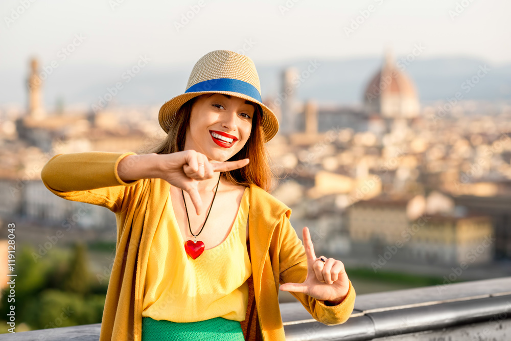 Young female traveler making photo frame with hands on the old city background in Florence in the mo