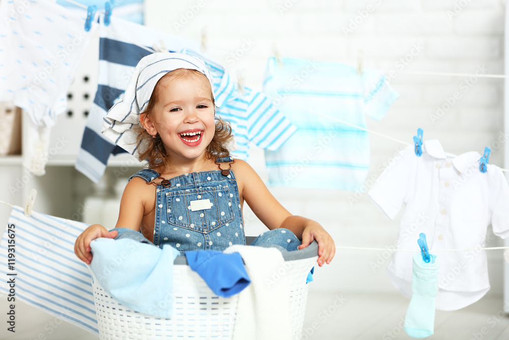 child fun happy little girl  to wash clothes and laughs in laund